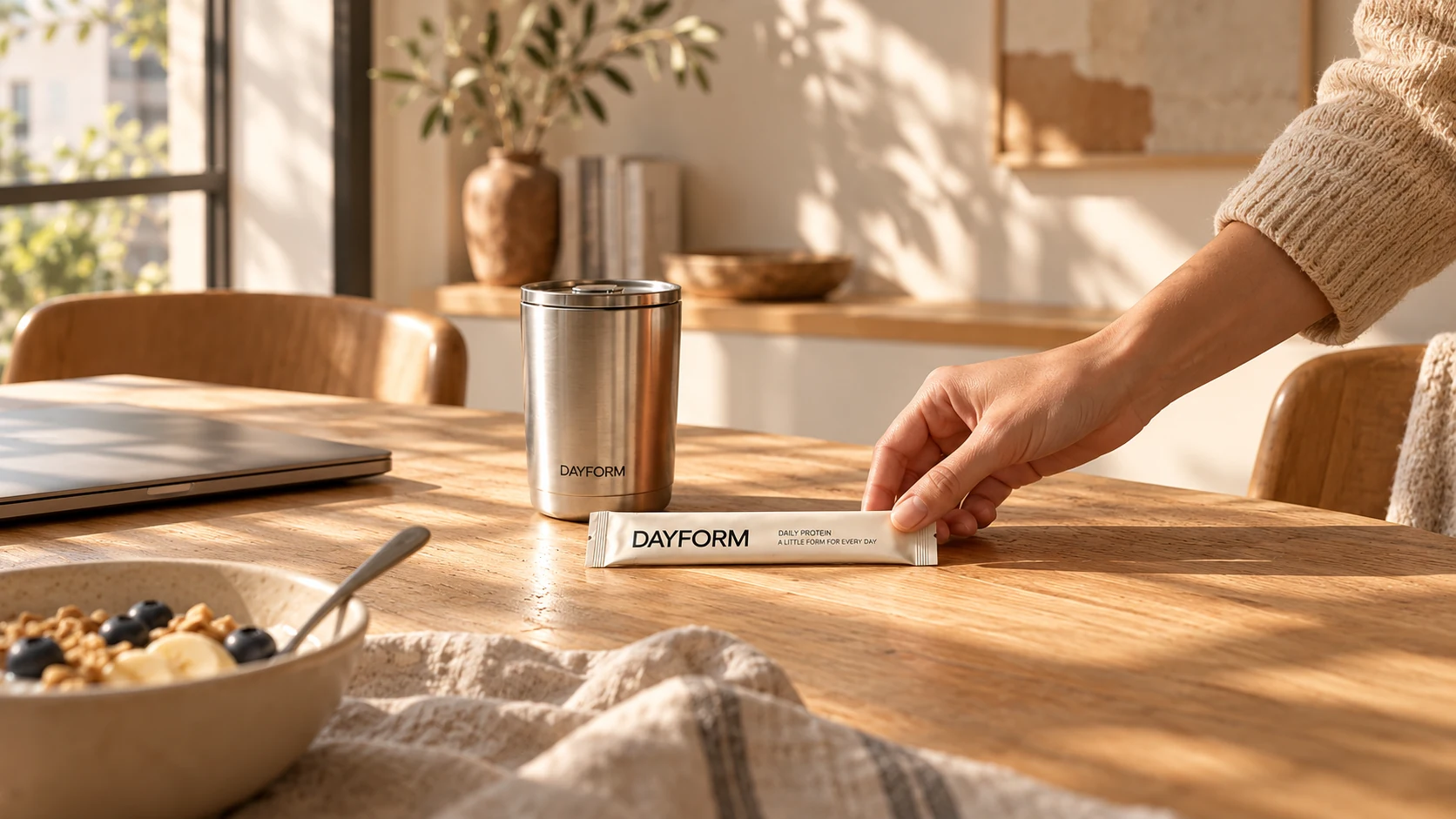 DAYFORM 场景概念:日光下的早餐桌,一只手将便携装放在杯具旁。